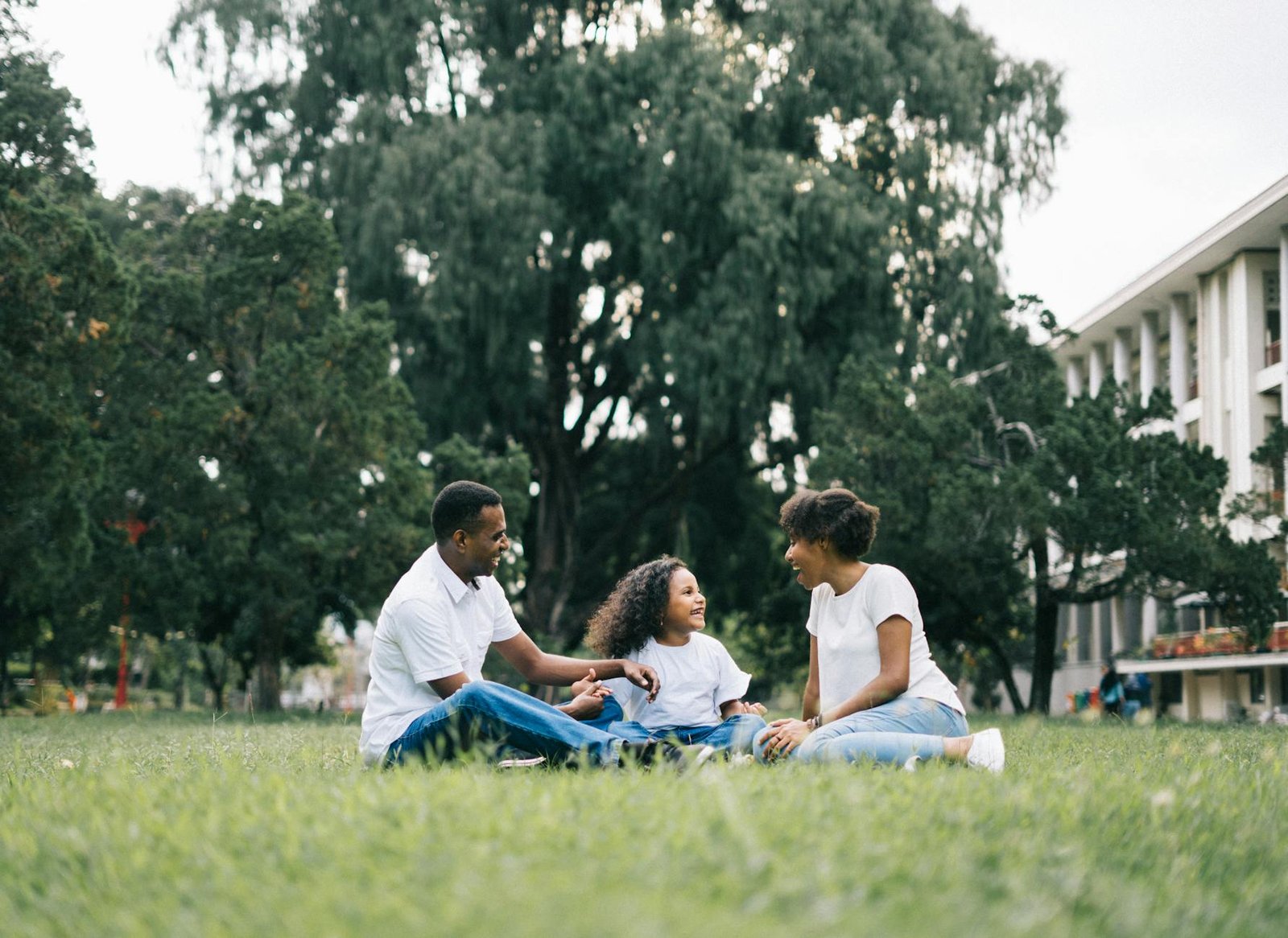 family sitting on grass near building