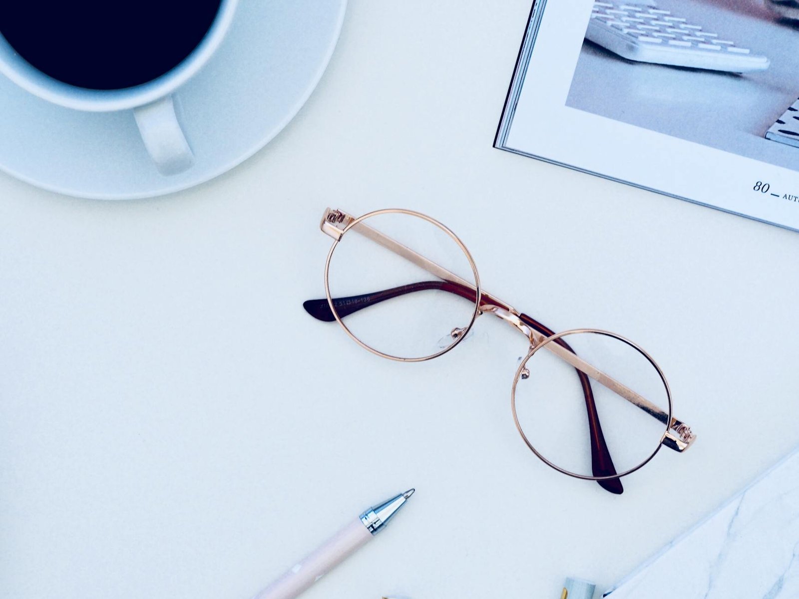 brown framed eyeglasses near cup of coffee on white surface