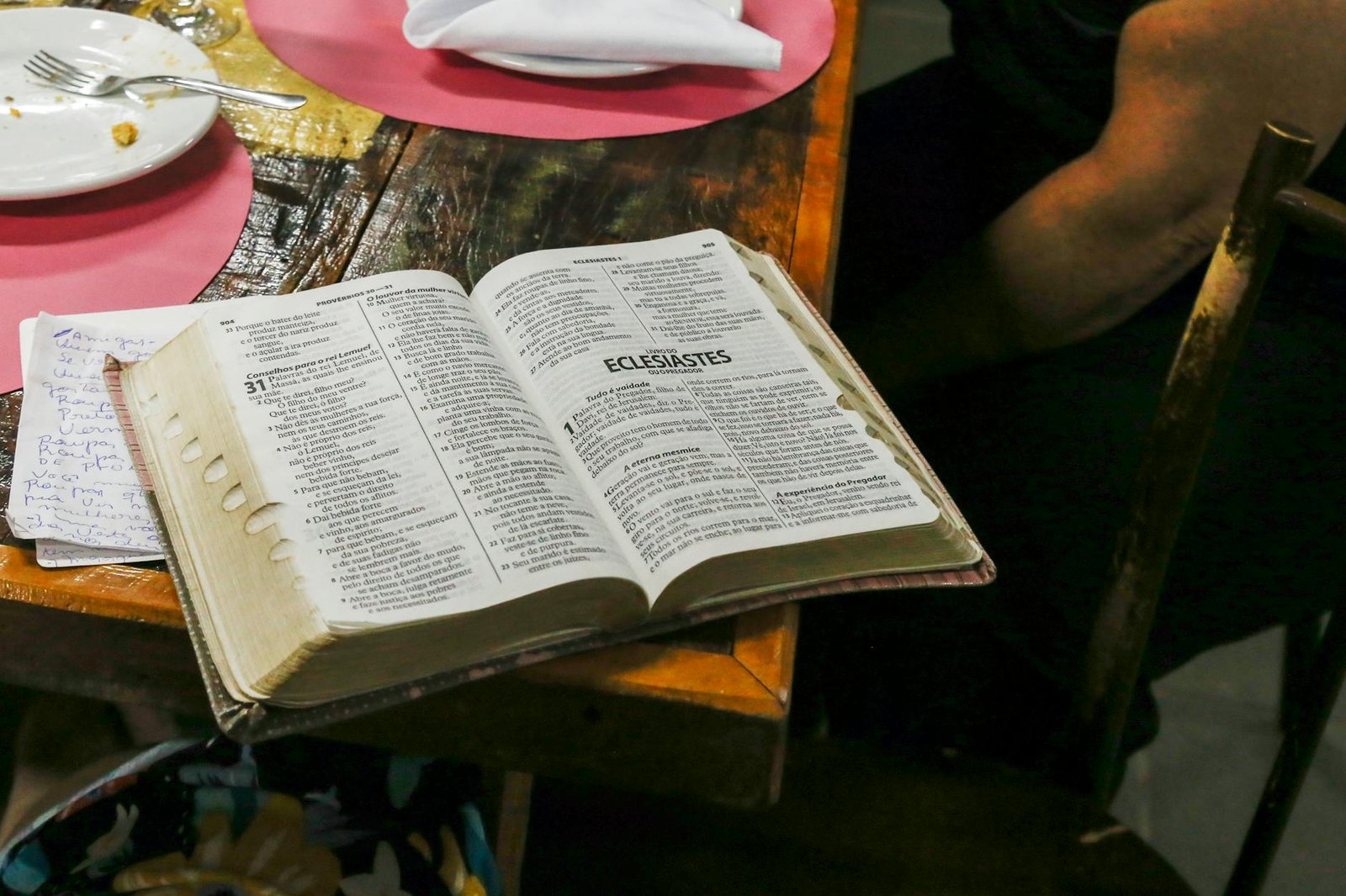 photo of opened bible book on brown table