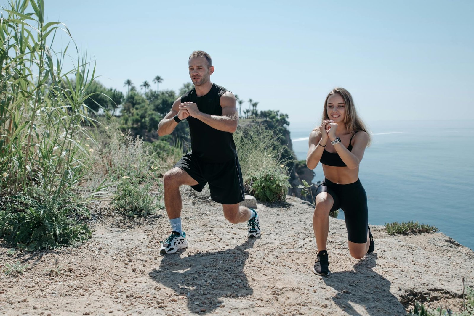 a man and woman working out near the cliff